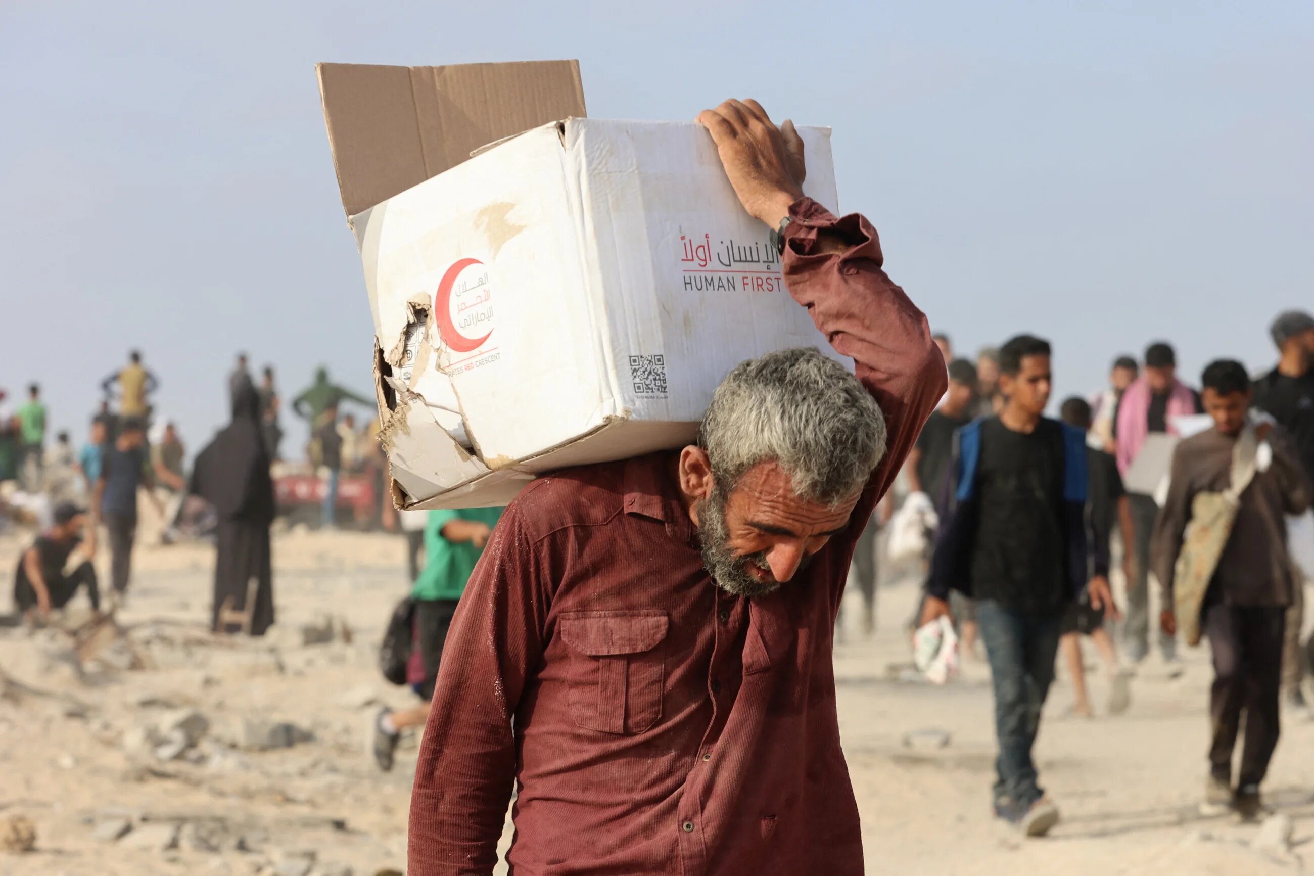 A Palestinian man carries a box of aid along al-Rashid street in western Jabalia on 22 June, 2025 (AFP/Omar al-Qattaa)