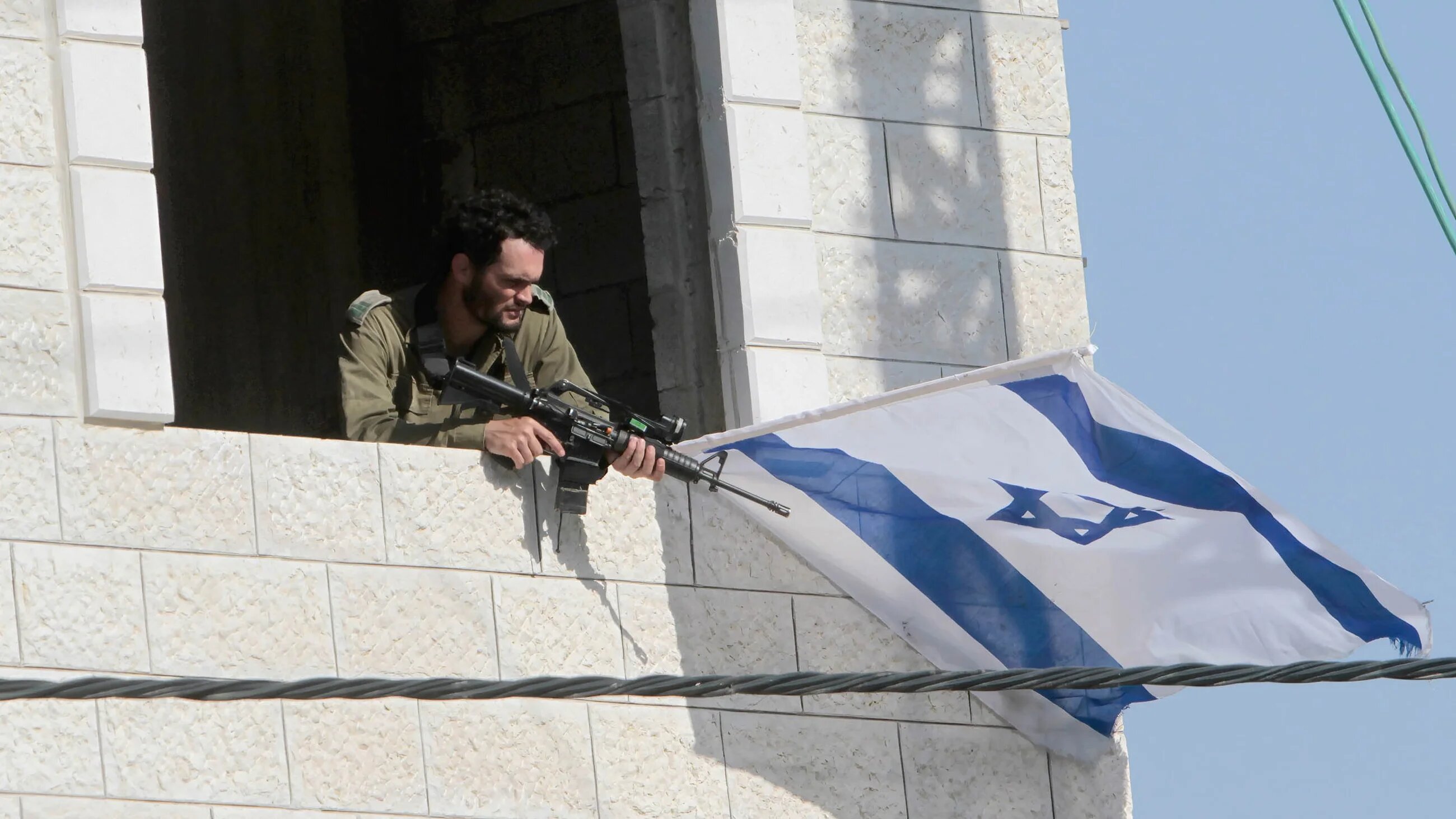 Israeli settlers raise Israeli flags on a building in the middle of the market in the town of Hawara, south of Nablus in the occupied West Bank. (Reuters)