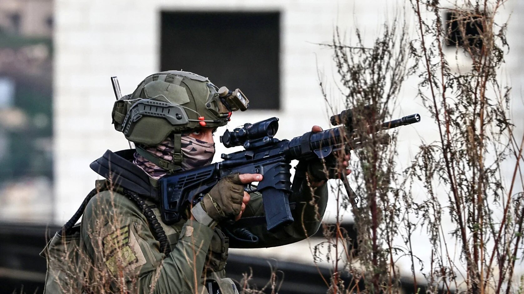 An Israeli soldier walks across an agricultural field at the entrance of the Tulkarem refugee camp in Tulkarem on 5 February 2025, as the army conducts a raid in the occupied West Bank city (AFP)
