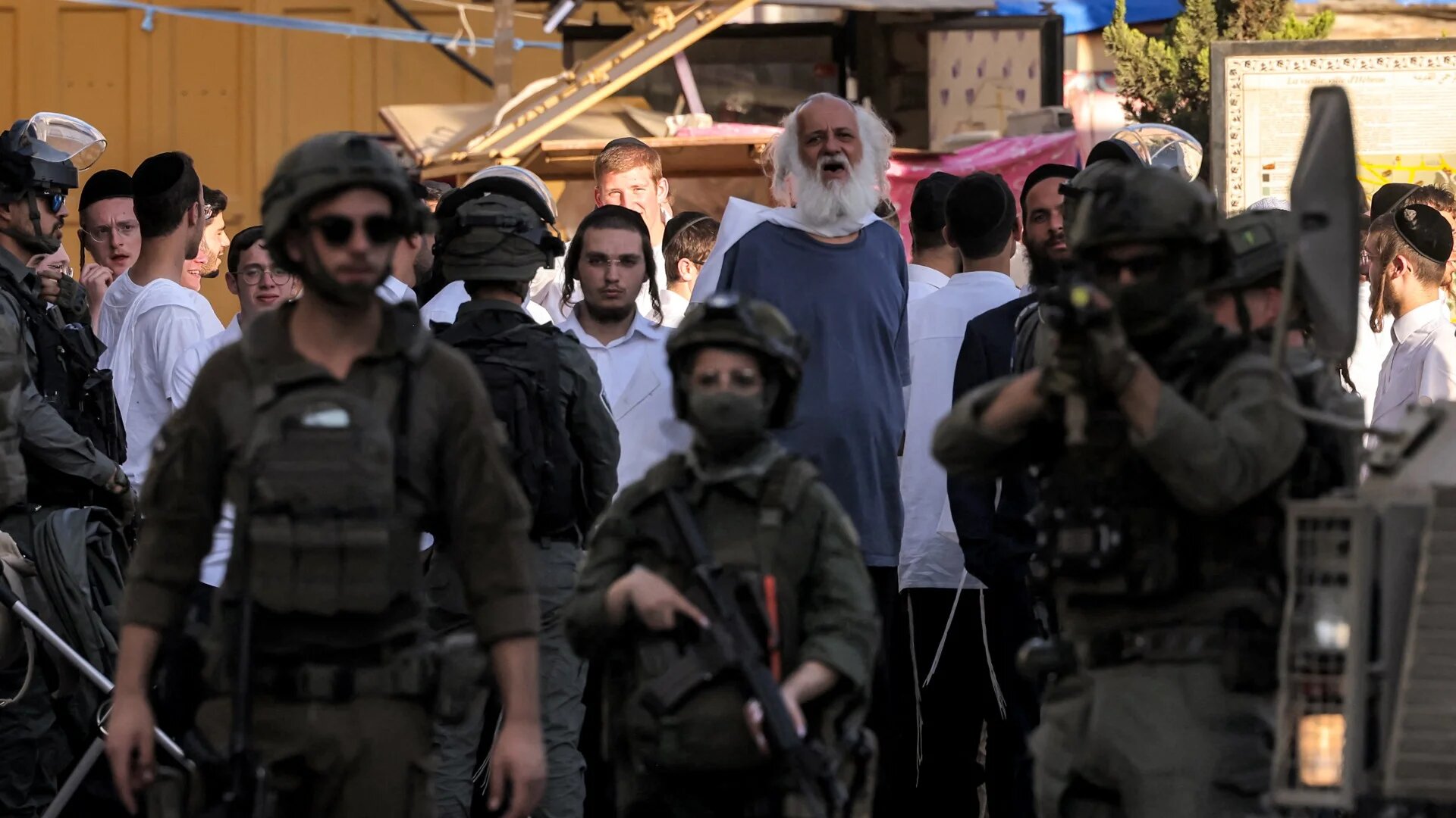 Israeli soldiers stand guard as Israeli settlers tour in the old city-centre and market of the Palestinian city of Hebron in the occupied West Bank on 28 June 2025 (AFP)