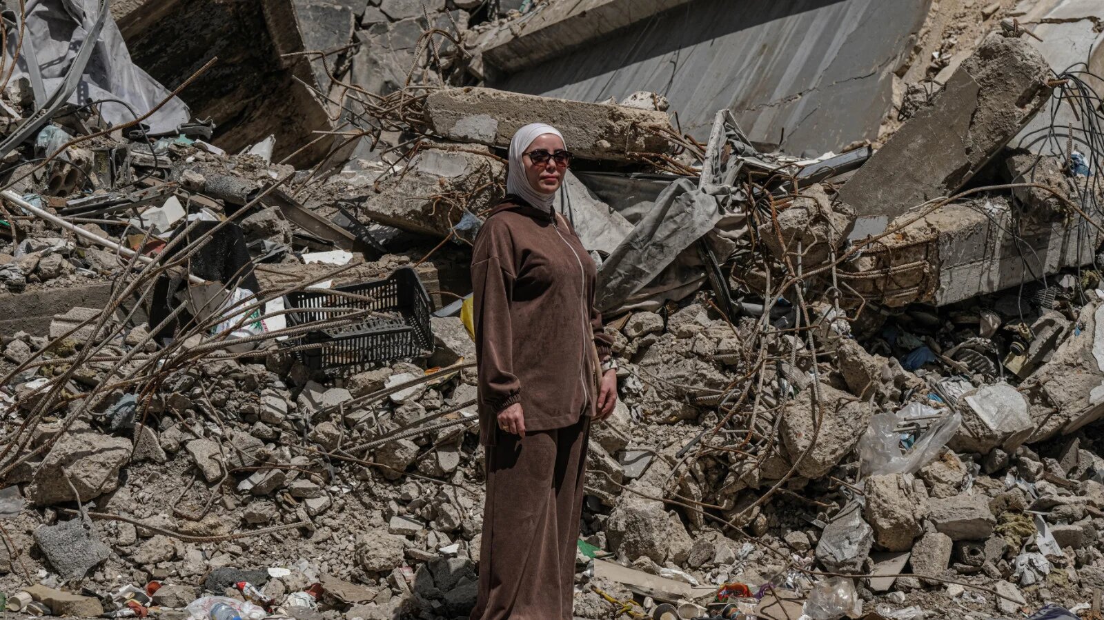 Naima poses in front of the rubble of the centre where her clinic once stood (Zaynab Mayladan/MEE)
