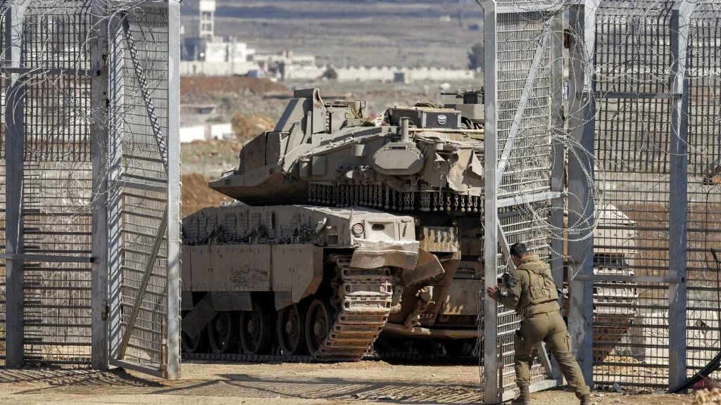 An Israeli soldier closes the gate behind a battle tank that crossed into the buffer zone separating Israeli and Syrian forces in the occupied Golan Heights on 2 March 2025 (Jalaa Marey/AFP)