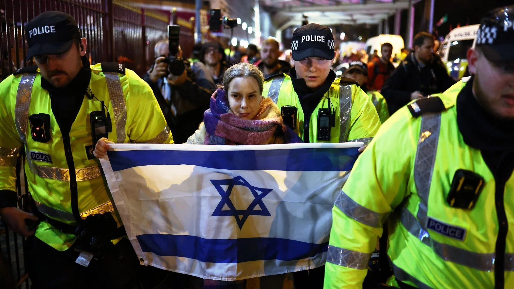 An Israel supporter is guarded by police officers during Aston Villa's match against Maccabi Tel Aviv on 6 November (AFP/Henry Nicholls)