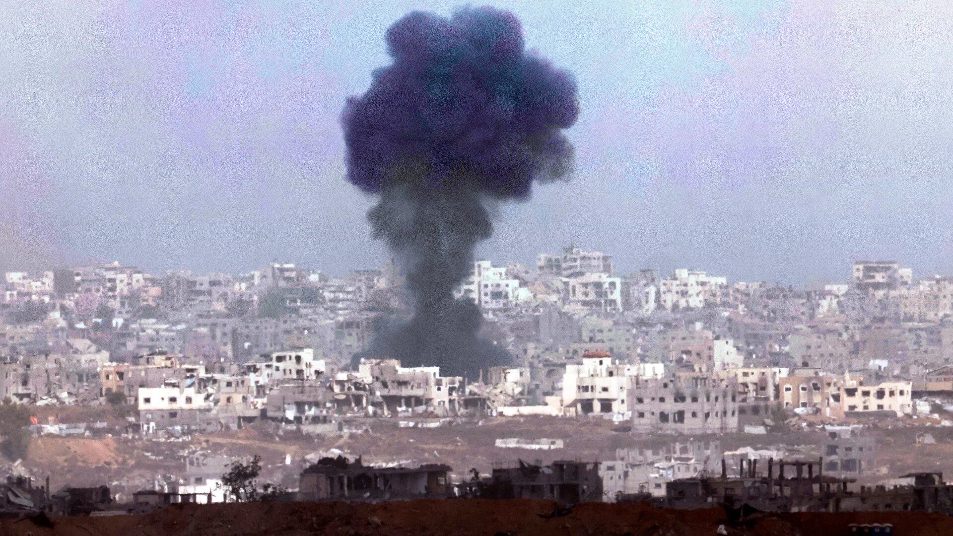 This picture taken from a position in southern Israel, shows smoke billowing above destroyed buildings during Israeli bombardment in the besieged Gaza Strip on 27 May 2025 (AFP/Jack Guez)