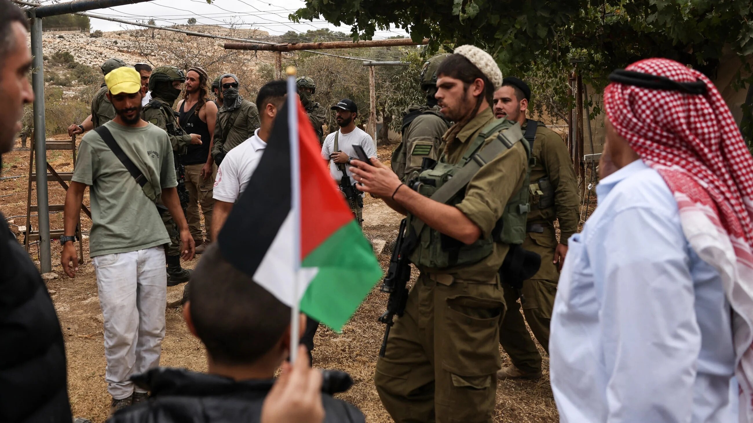 Israeli soldiers and settlers restrict Palestinian villagers during the olive harvesting season in Hebron, occupied West Bank, on 12 October, 2025 (AFP/Hazem Bader)