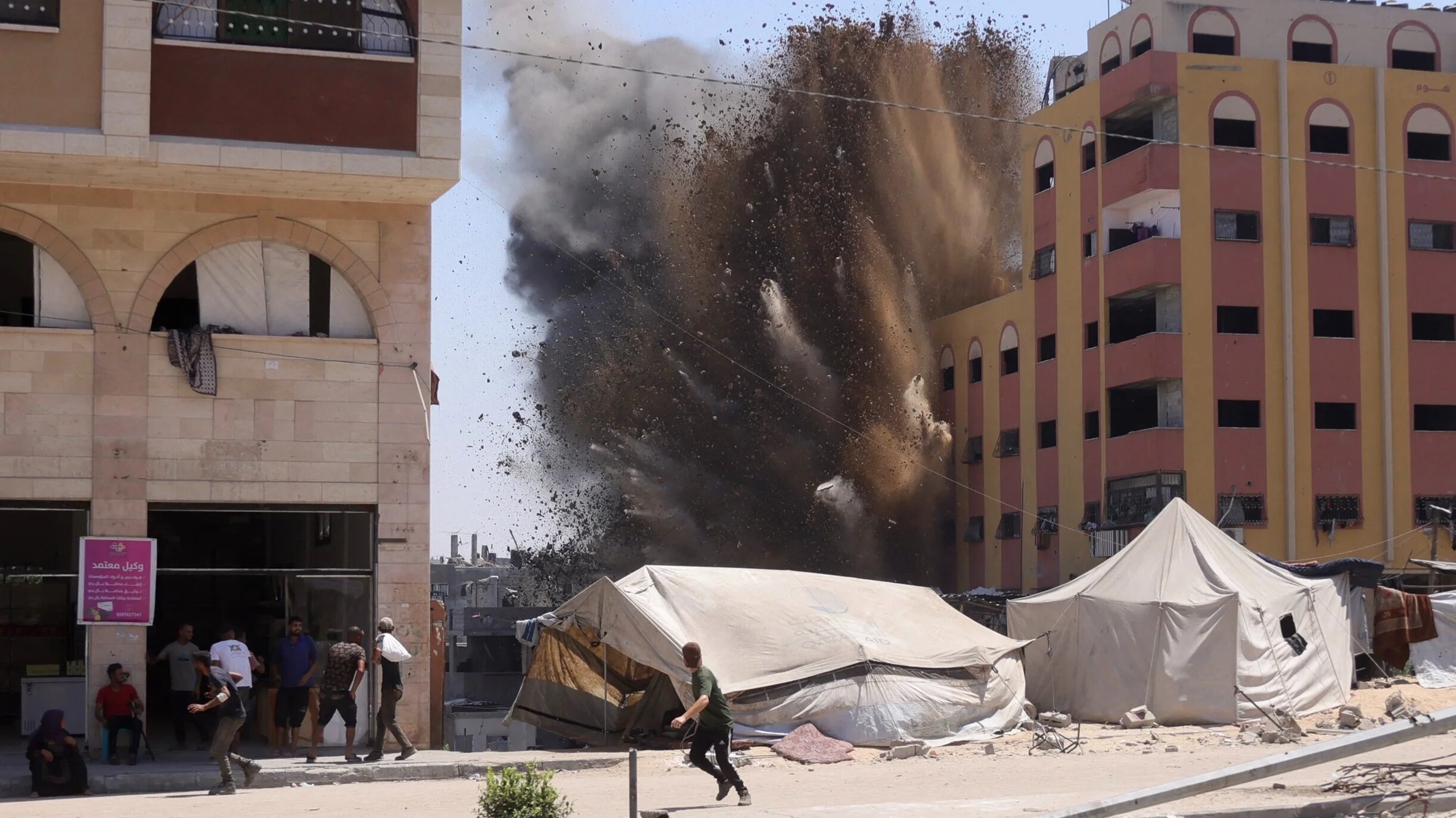 Palestinians rush for cover as smoke billows after an Israeli strike on a building in Jabalia in the northern Gaza Strip on 20 August 2025 (AFP/Bashar Taleb)