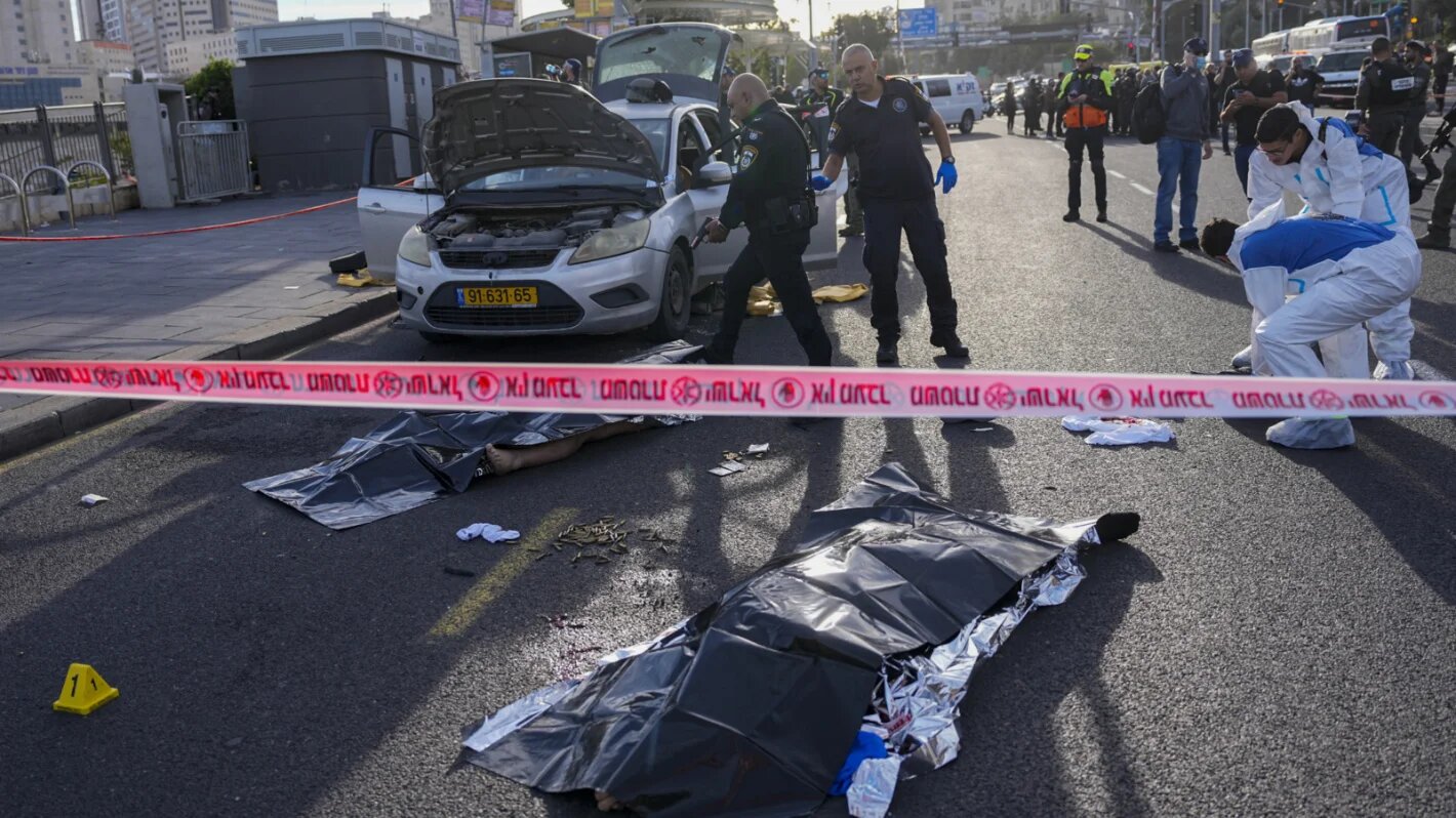 Israeli police officer pointing his gun at killed Palestinian attacker