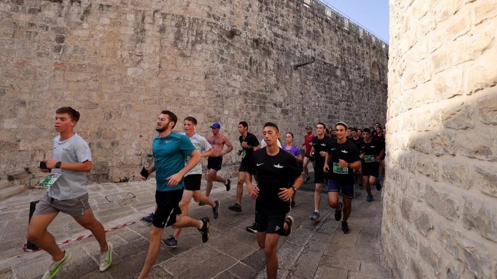 Runners run through the Old City in East Jerusalem in 2021 (AFP)