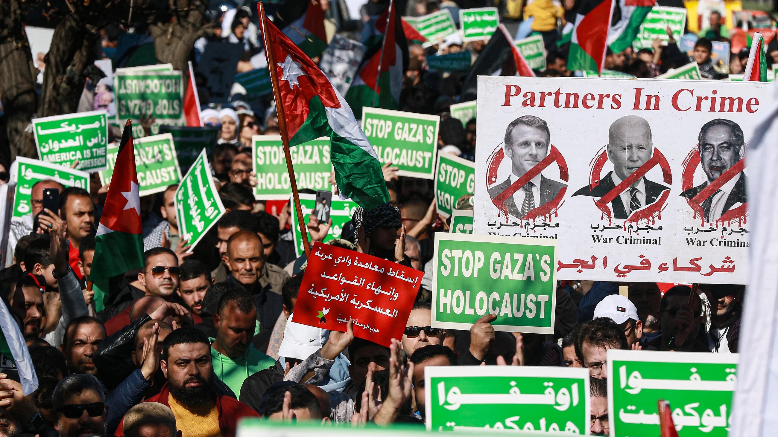 People wave Palestinian and Jordanian flags as they march during a demonstration near the US embassy in Amman in solidarity with the people of Gaza on 15 December 2023 (Khalil Mazraawi/AFP)