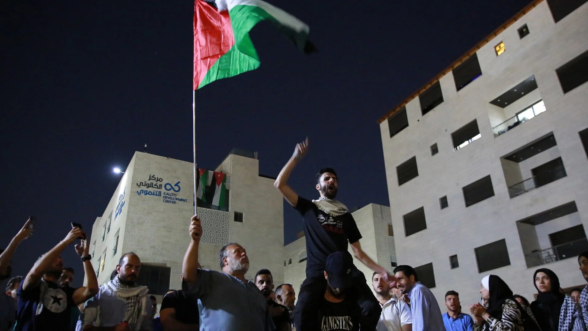 A man waves a Palestinian flag as people protest near the Israeli embassy in the Jordanian capital Amman on 1 August 2024 (AFP)