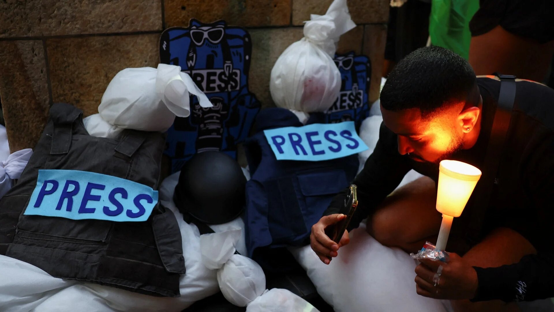 A man holds a candle during a vigil to remember journalists killed and wounded in Gaza outside the St George's Cathedral, in Cape Town, South Africa, January 28, 2024 (Reuters)
