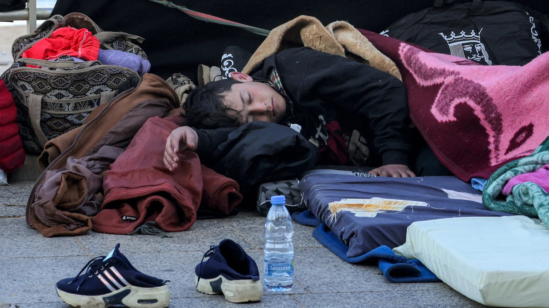 A child sleeps alongside family belongings in a makeshift encampment along the waterfront in Beirut on 10 March 2026 (AFP)
