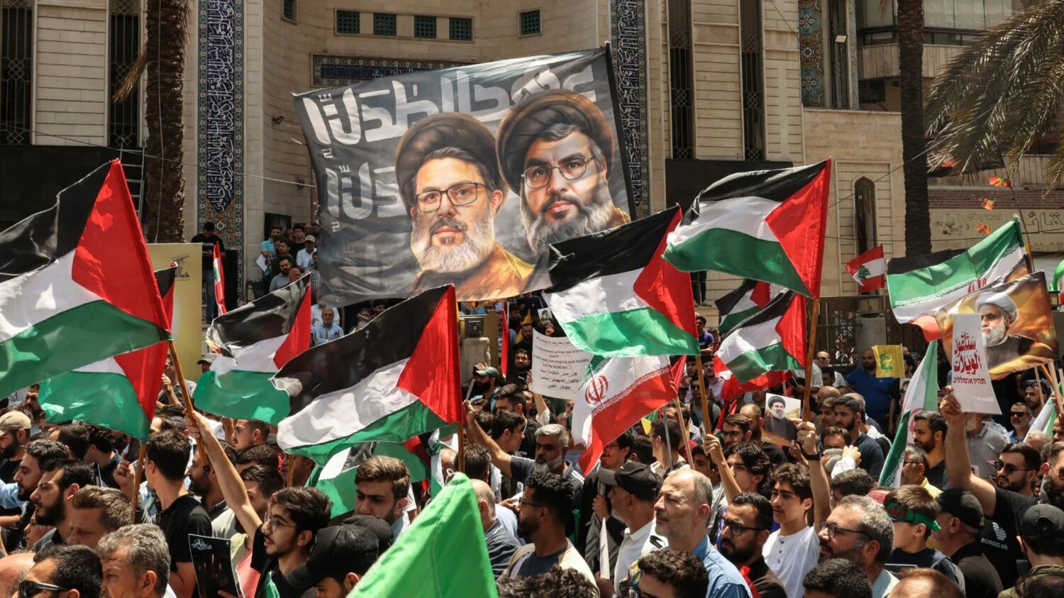 Hezbollah supporters wave Palestinian and Iranian flags in support of Iran  in Beirut's southern suburbs in June 2025 (AFP)