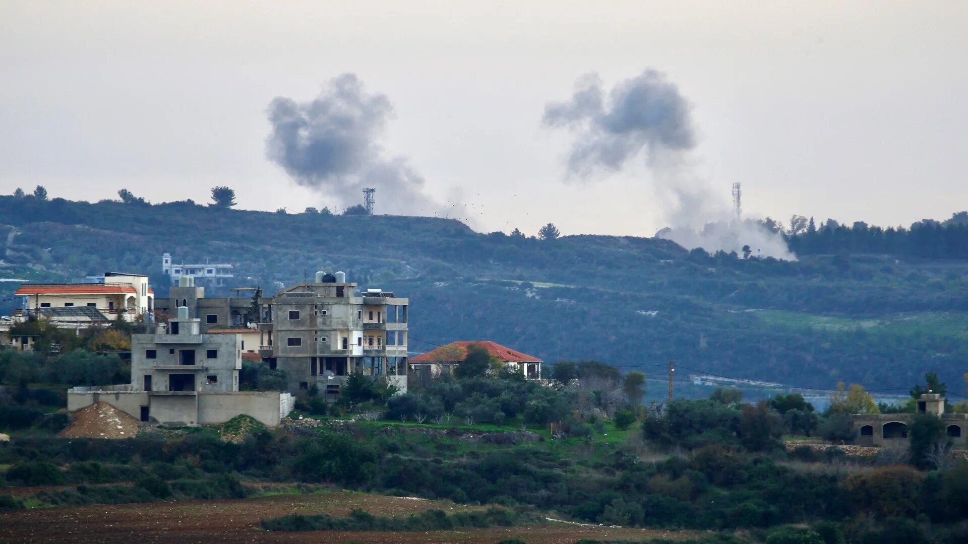 This photograph taken on January 5, 2024 shows buildings in the southern Lebanese town of Tair Harfa as smoke billows over northern Israel (AFP)