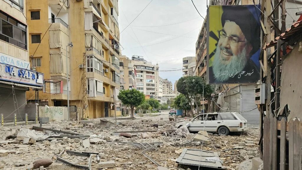 A banner bearing the image of slain Hezbollah leader Hassan Nasrallah hangs near the site of an Israeli air strike in Beirut’s southern suburbs, on 25 March 2026 (AFP)