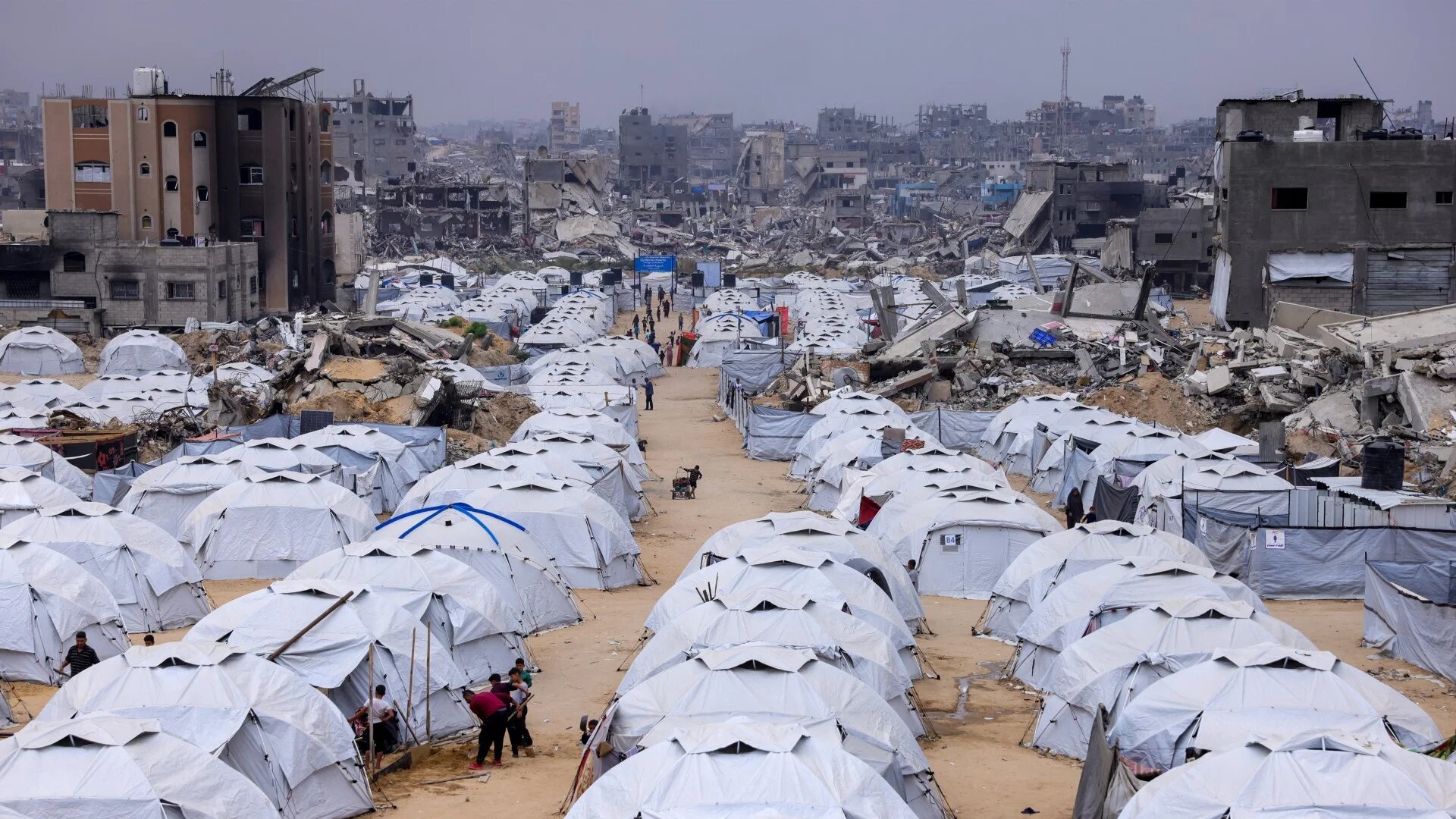 People walking amid tents set up next to the rubble of destroyed buildings at the Jabalia camp for displaced Palestinians in the northern Gaza Strip on 8 April 2025 (AFP/Bashar Taleb)