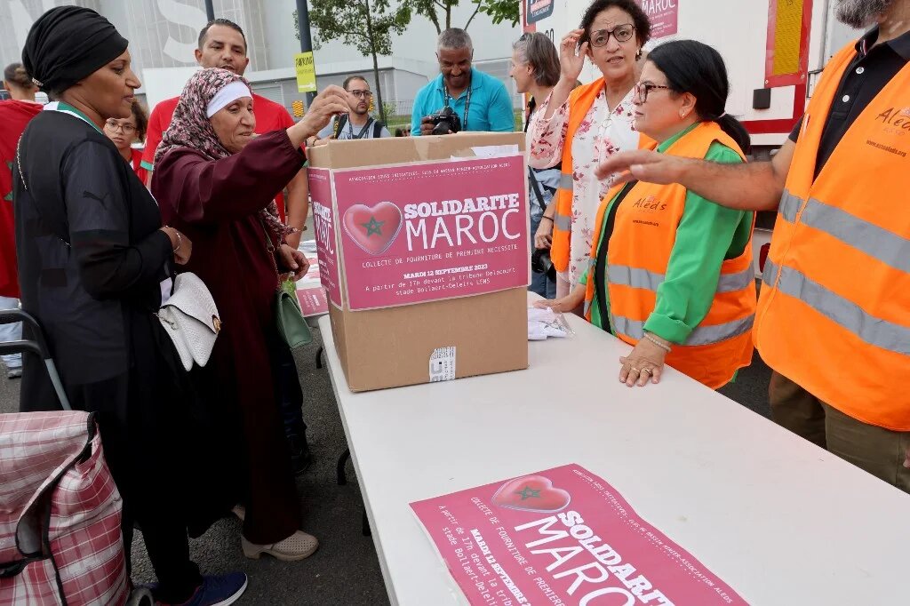 Une femme fait un don pour les victimes du séisme au Maroc à un point de collecte en marge du match de football amical international entre le Maroc et le Burkina Faso au Stade Bollaert-Delelis à Lens, dans le nord de la France, le 12 septembre 2023 (AFP/Denis Charlet)