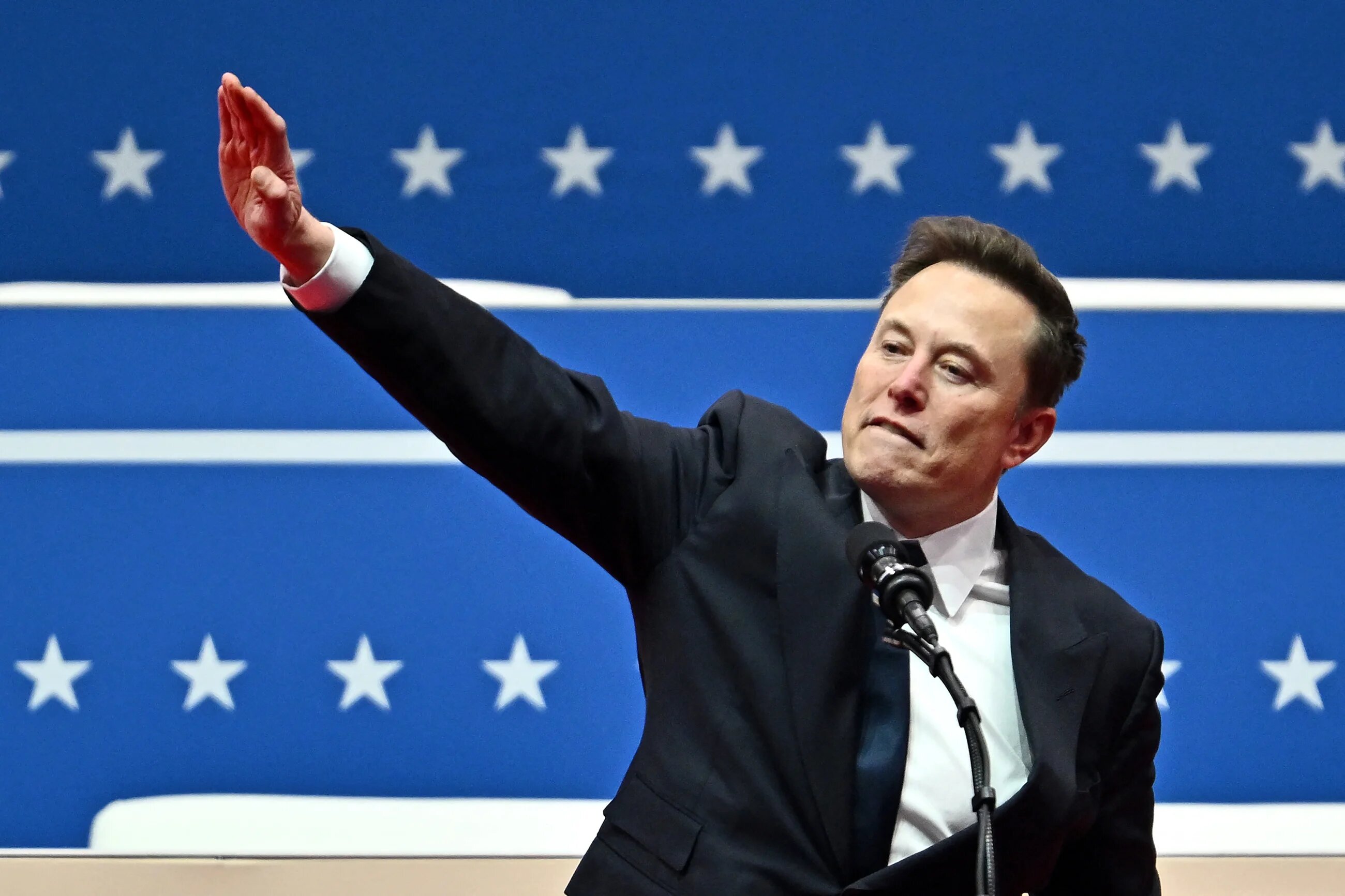 Tesla and SpaceX CEO Elon Musk salutes as he speaks during the inaugural parade inside Capital One Arena in Washington on 20 January 2025 (AFP)