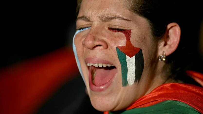 A demonstrator with the Palestinian flag painted on her face shouts slogans during a march in Buenos Aires, Argentina, on 7 October 2025 (Luis Robayo/AFP)