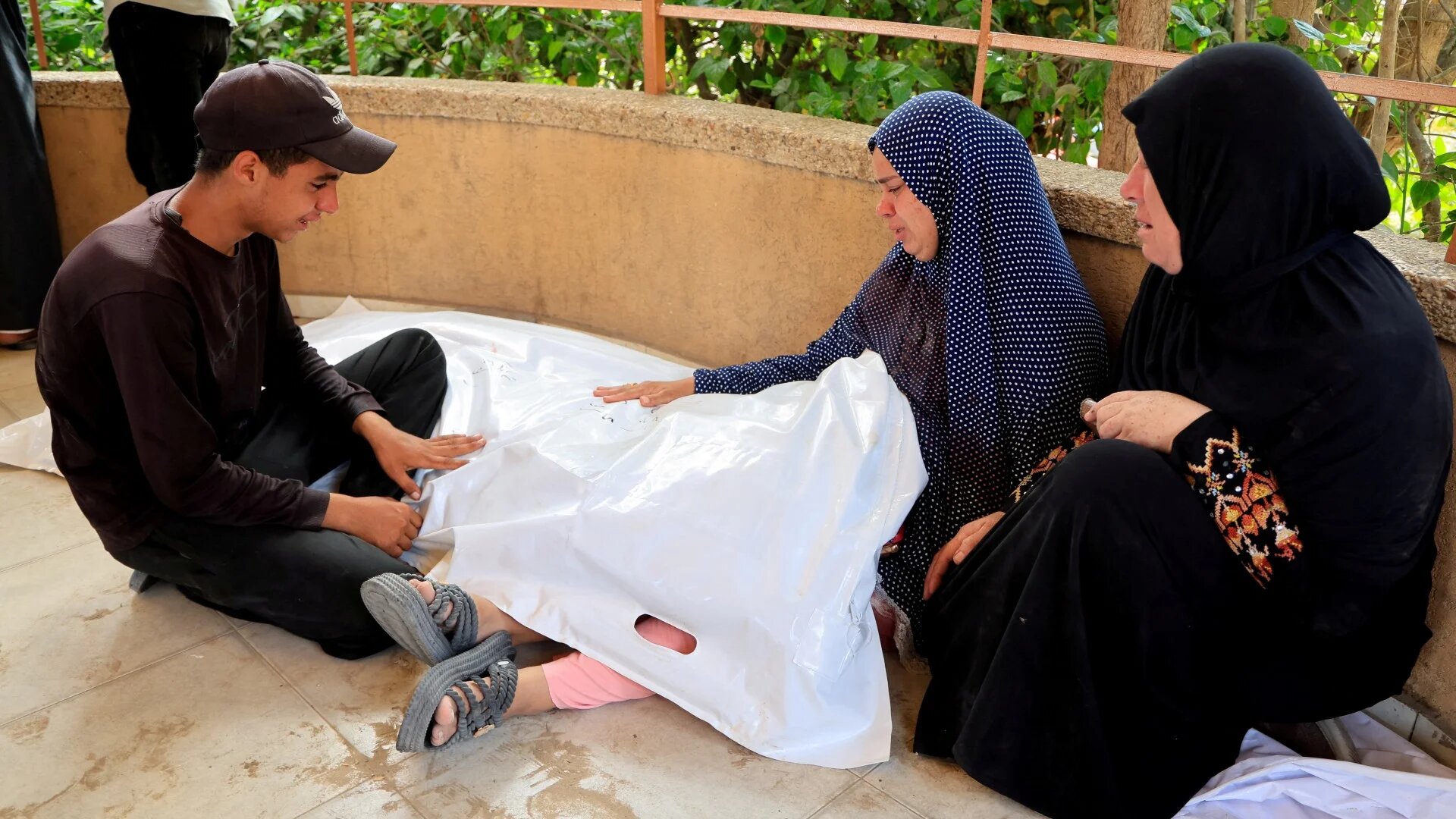 A Palestinian family mourns after their relative, a child, Alees, was killed in Israeli strikes on tents sheltering displaced people on 14 July 2025 in the southern Gaza Strip (Hatem Khaled/Reuters)