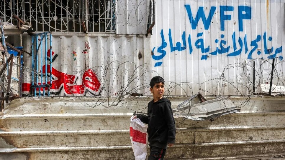 A boy walks with an empty sack past a shuttered bakery in Gaza City on 1 April 2025 (Bashar Taleb/AFP)