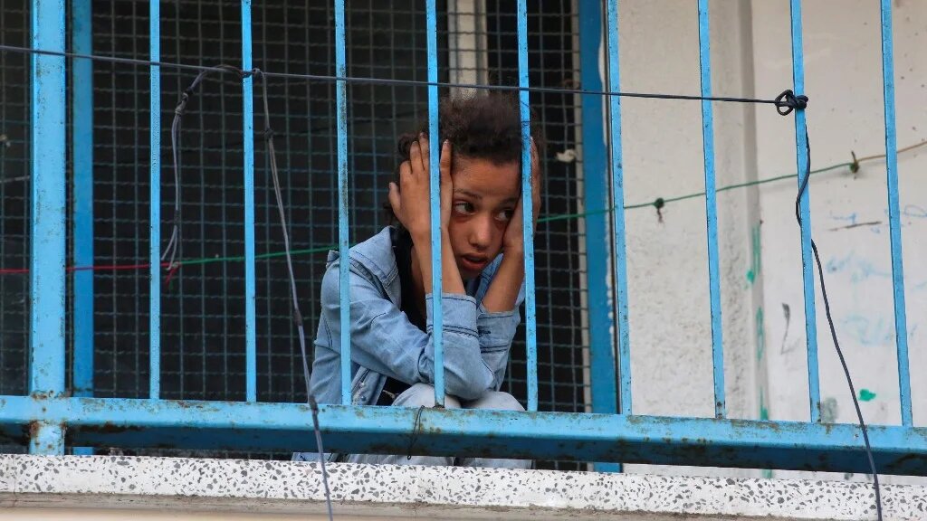 A Palestinian girl looks at a makeshift displacement tent camp that was hit in Israeli strikes at the Bureij refugee camp in central Gaza on 17 July 2025 (Eyad Baba/AFP)