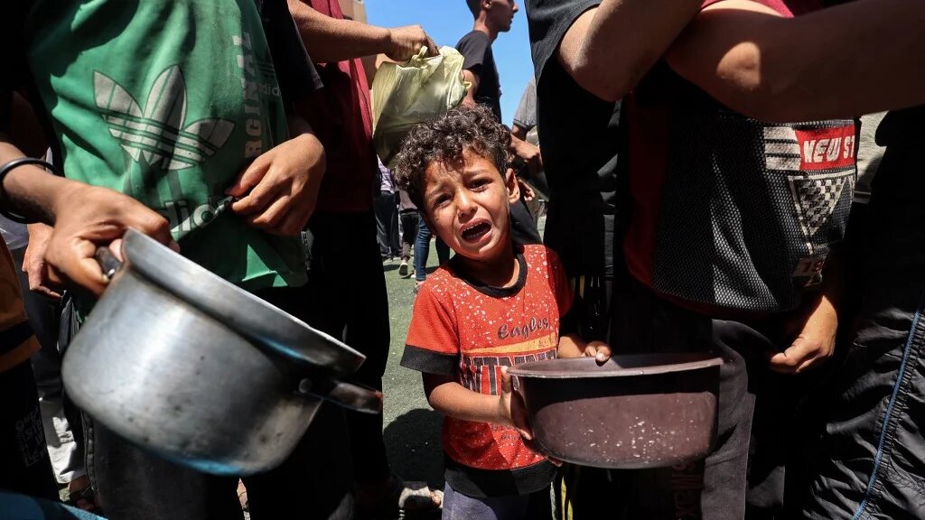 A child cries as Palestinians gather to receive a hot meal at a food distribution point in the Nuseirat refugee camp in central Gaza on 24 May 2025 (Eyad Baba/AFP)