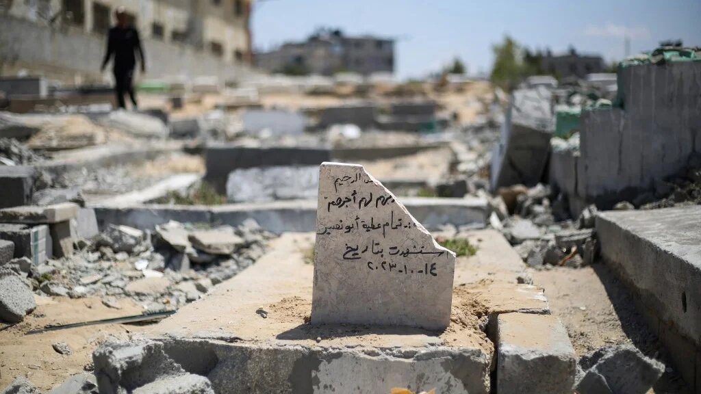Palestinians walk among damaged graves after an Israeli strike in Deir al-Balah, central Gaza, on 3 June 2025 (Eyad Baba/AFP)