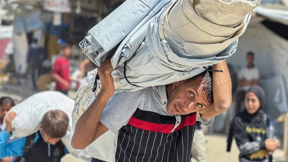 Palestinians carry their belongings after Israel ordered residents to flee Khan Younis, in the southern Gaza Strip, on 19 May 2025 (AFP)