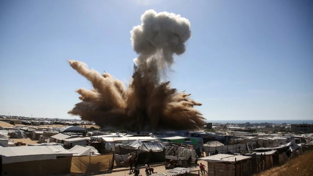 A plume of smoke rises above tents at a camp for displaced Palestinians in Khan Younis, Gaza, after an Israeli strike on 19 April 2025 (AFP)