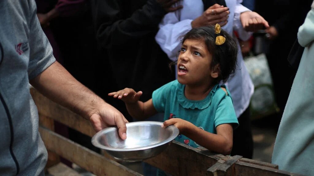 A Palestinian girl holds an empty pan at a hot meal distribution point in Nuseirat, Gaza, on 4 June 2025 (Eyad Baba/AFP)