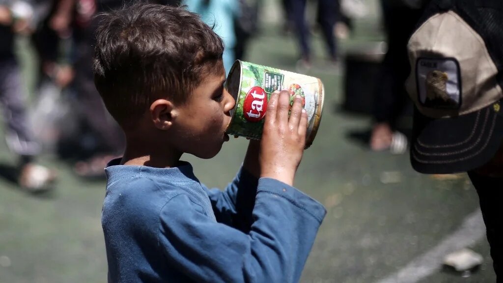 A Palestinian child eats his portion of a hot meal at a food distribution point in Gaza’s Nuseirat camp on 19 April 2025 (Eyad Baba/AFP)