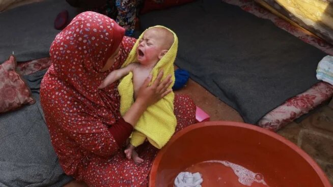 A woman and baby are pictured inside a tent at a camp for displaced Palestinians in Rafah, Gaza, on 18 January 2024 (Mohammed Abed/AFP)