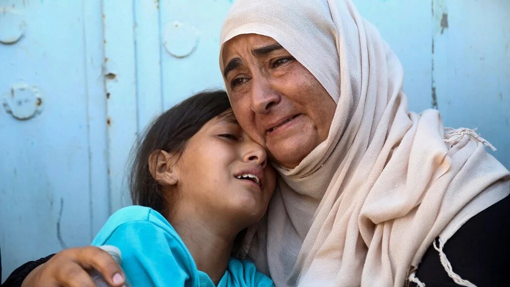 A woman and child react after identifying the body of a family member at Gaza’s Nasser hospital, among Palestinians killed in Israeli strikes in the territory’s south on 24 July 2025 (AFP)