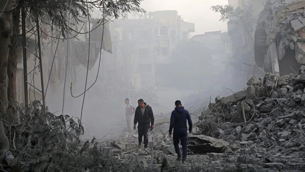 Men look for their belongings amid the rubble of destroyed buildings in the central Gaza Strip on 12 January 2025 (Eyad Baba/AFP)