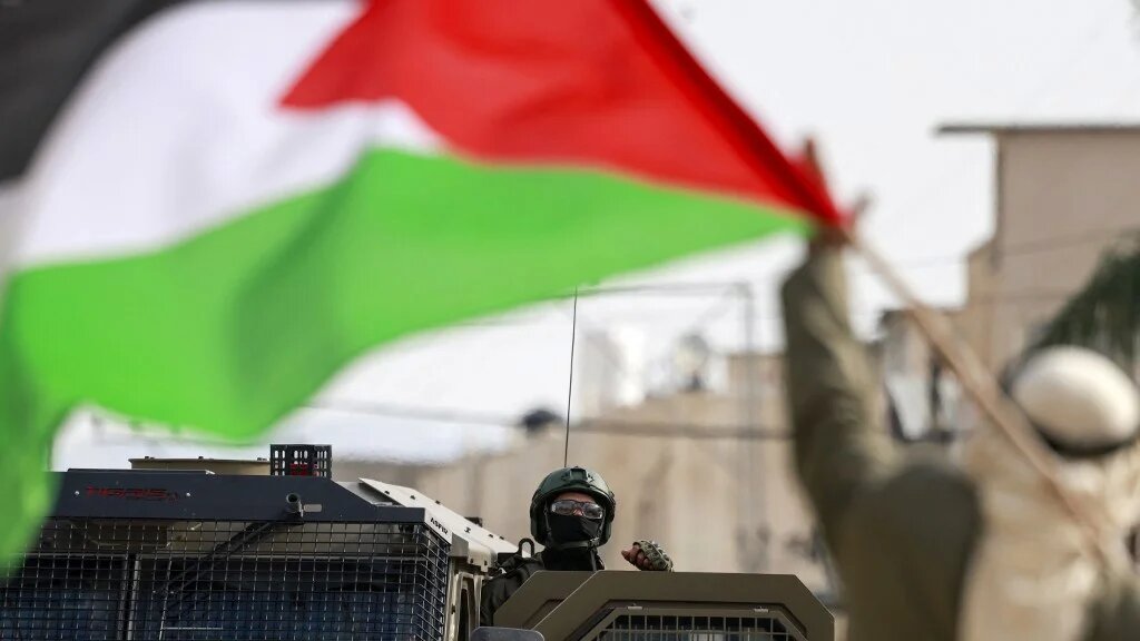 A Palestinian man gestures towards an Israeli soldier outside the Nur Shams refugee camp, in the Israeli-occupied West Bank, on 15 December 2025 (Jaafar Ashtiyeh/AFP)