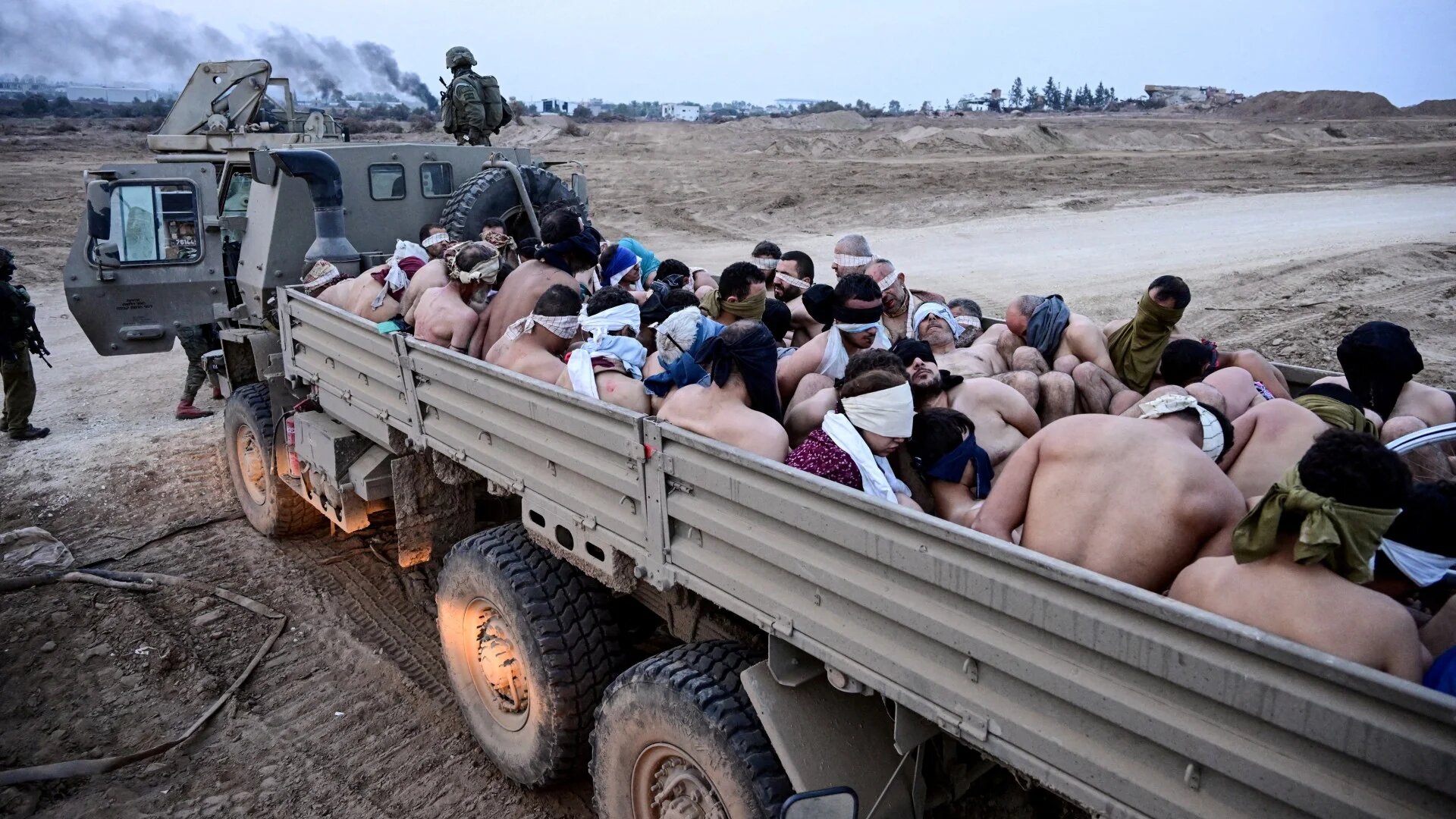Israeli soldiers guard Palestinian captives in Gaza on 8 December 2023 (Yossi Zeliger/Reuters)