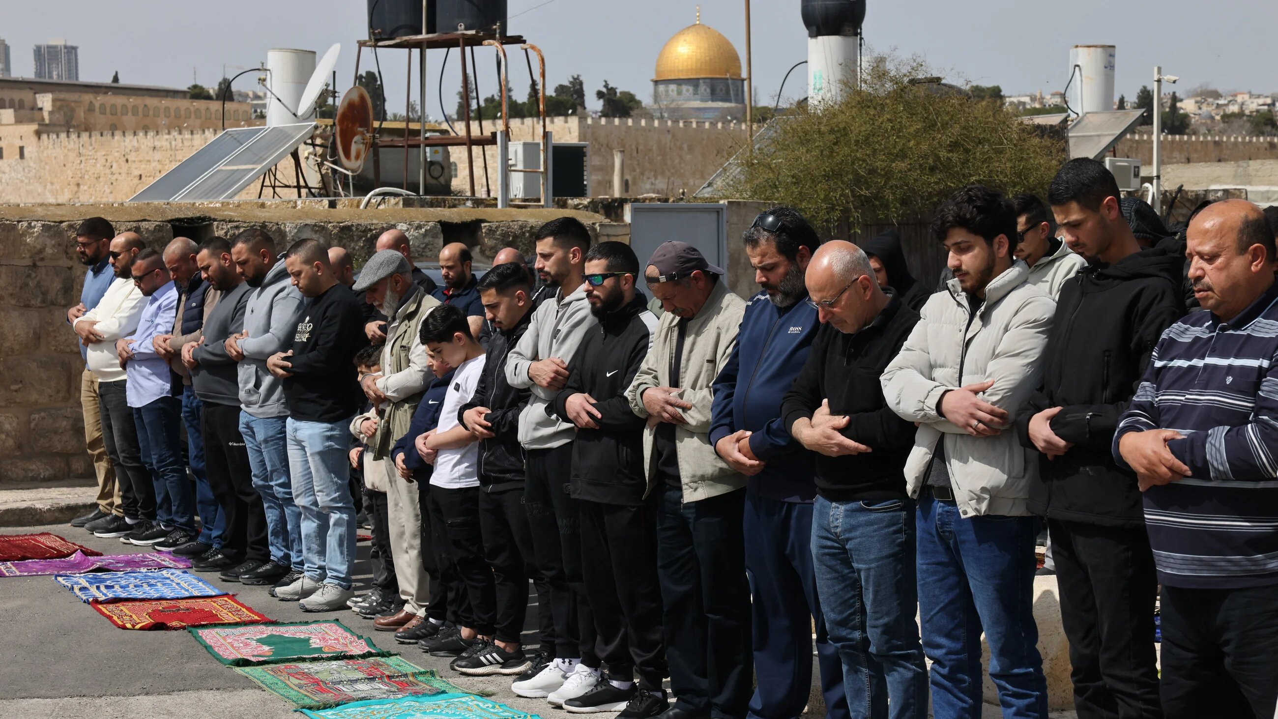 Palestinian Muslim worshippers attend prayers by a road, as they are not permitted to enter Al-Aqsa Mosque complex amid Israeli restrictions, in Jerusalem on 13 March 2026 (Ammar Awad/Reuters)