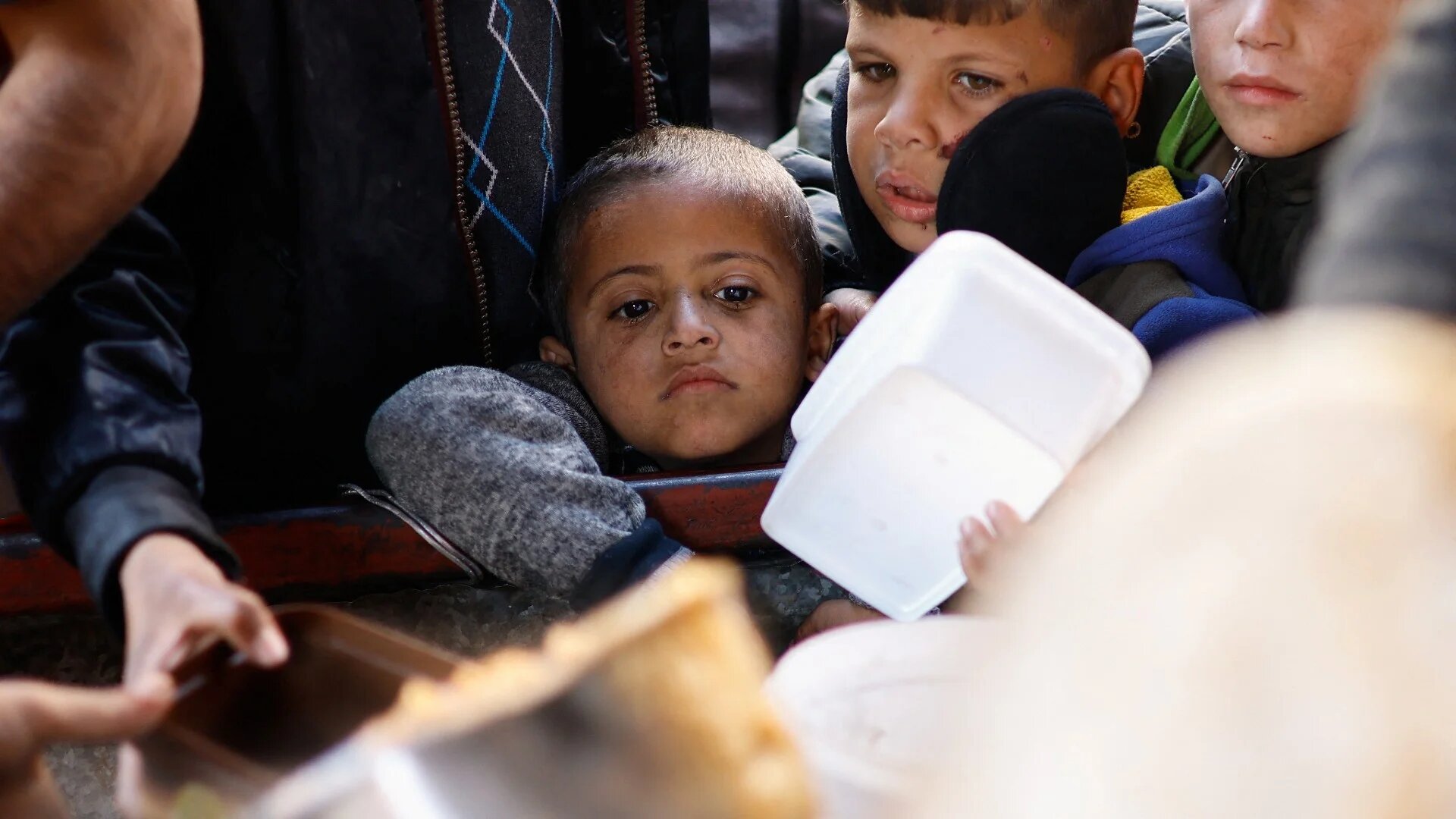 Palestinians wait to receive food cooked by a charity kitchen amid shortages of food supplies in Rafah in the southern Gaza Strip, on 16 January, 2024 (Reuters)