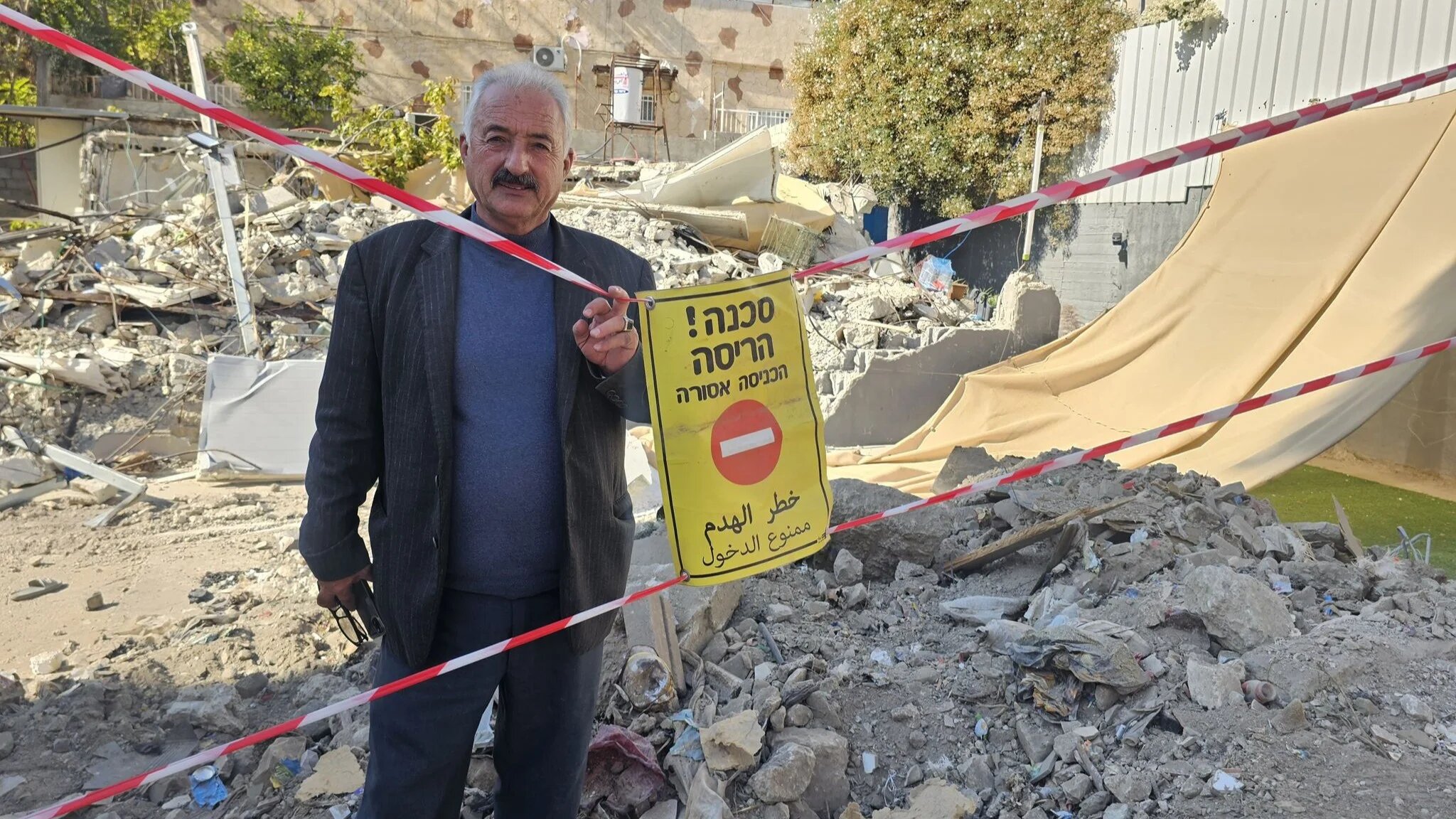 Fakhri Abu Diab, a local activist and resident of Silwan, located in Israeli-occupied East Jerusalem, stands beside the rubble of his demolished home (Provided)