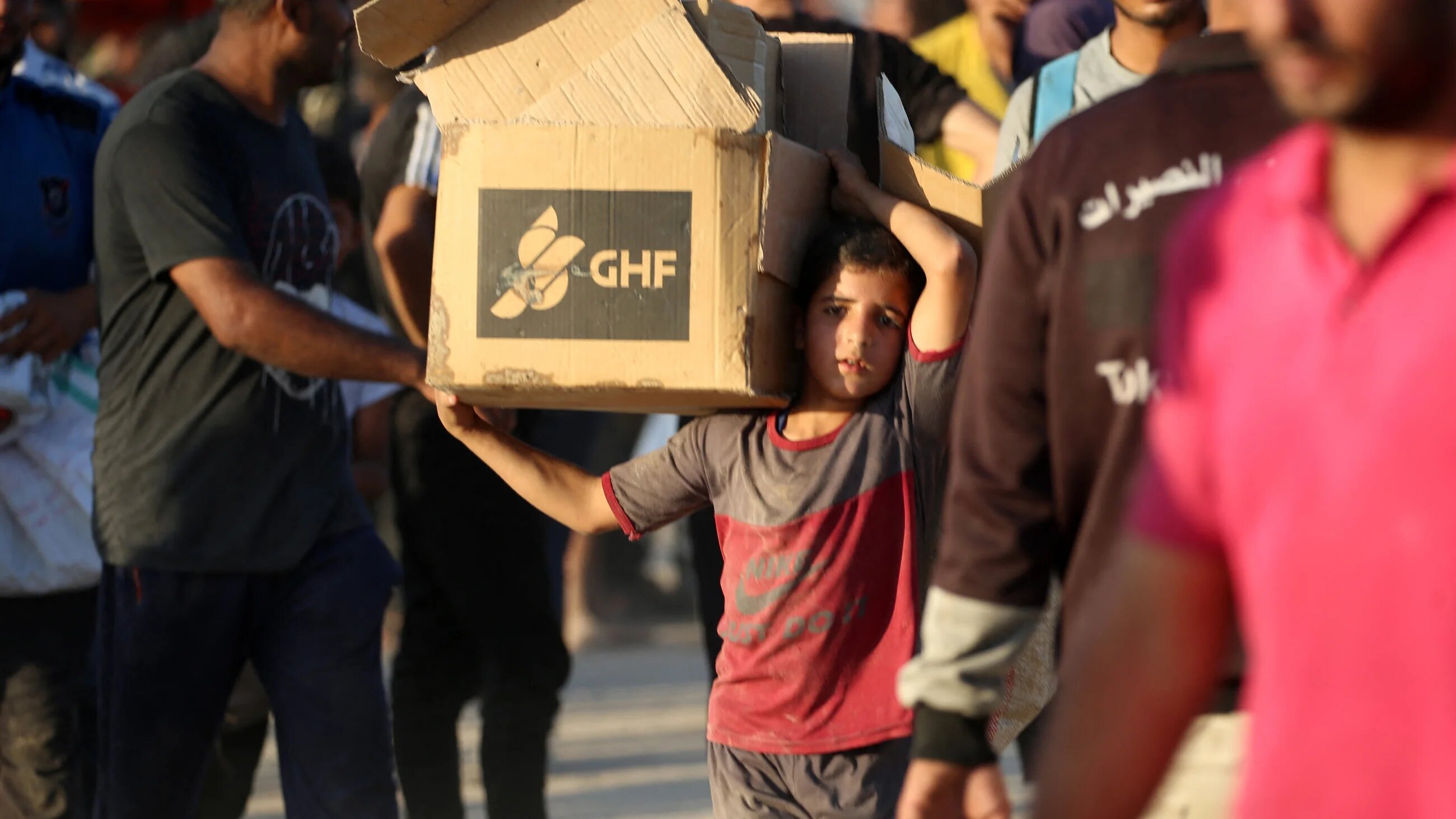 A Palestinian boy carries an aid parcel from the Gaza Humanitarian Foundation (GHF), which has been largely criticised for its militarised relief distribution mechanism, on 25 June 2025 (AFP/Eyad Baba)
