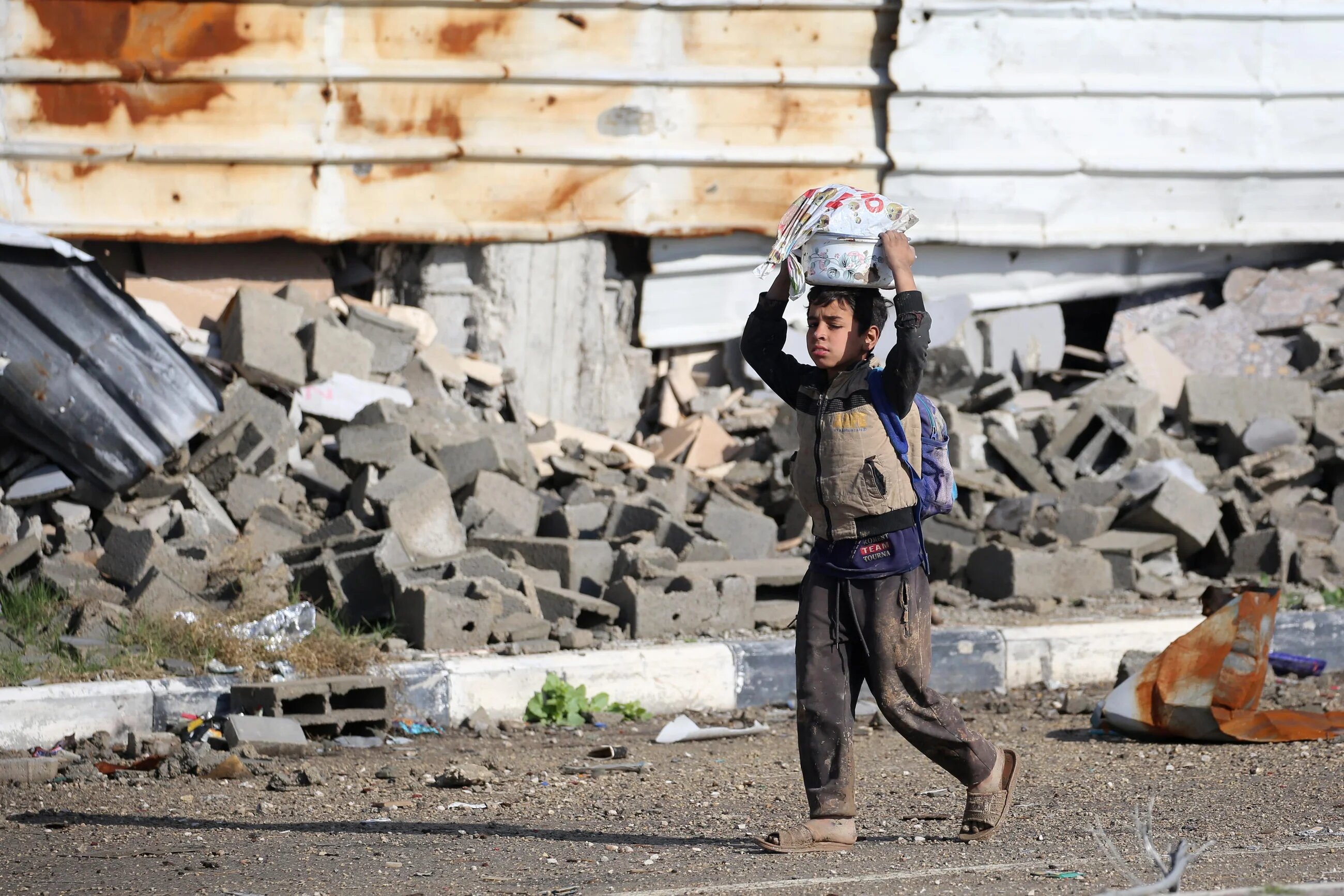 A Palestinian child carries a container on his head in al-Mughraqa, central Gaza Strip (AFP/Eyad Baba)