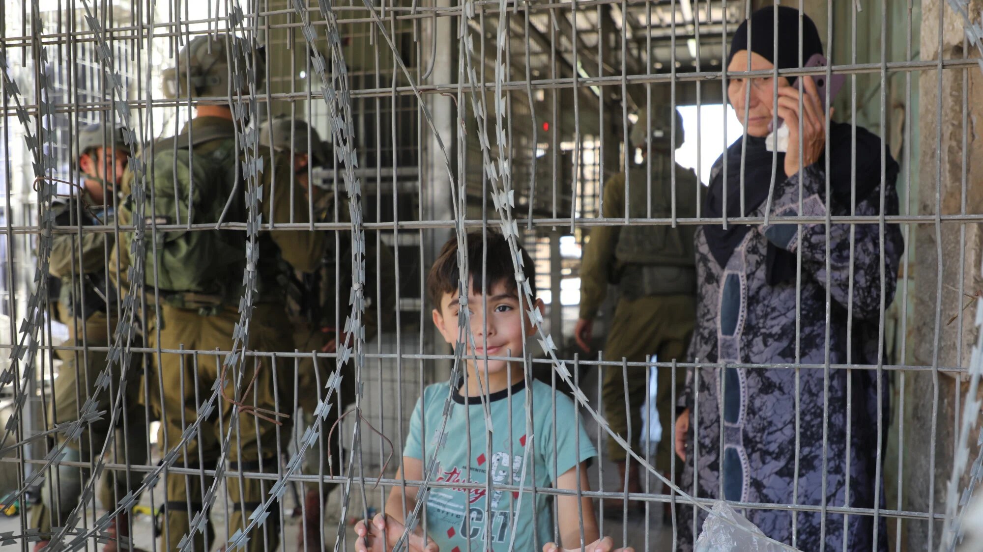 A Palestinian child stands at an Israeli checkpoint in Hebron (MEE/Mosab Shawar)