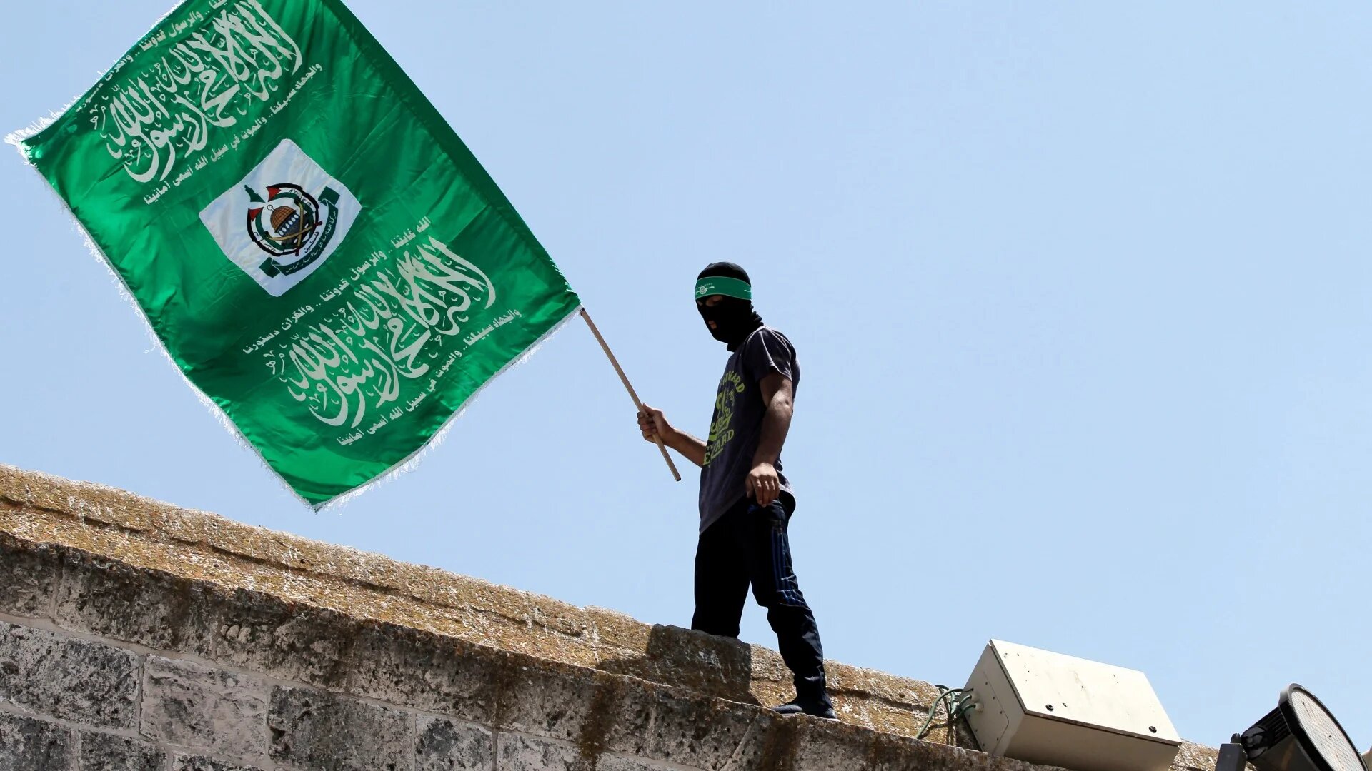 A Palestinian man waves the green flag of Hamas during a demonstration outside the Al-Aqsa Mosque compound in Jerusalem on 3 July 2015 (Ahmad Gharabli/AFP)