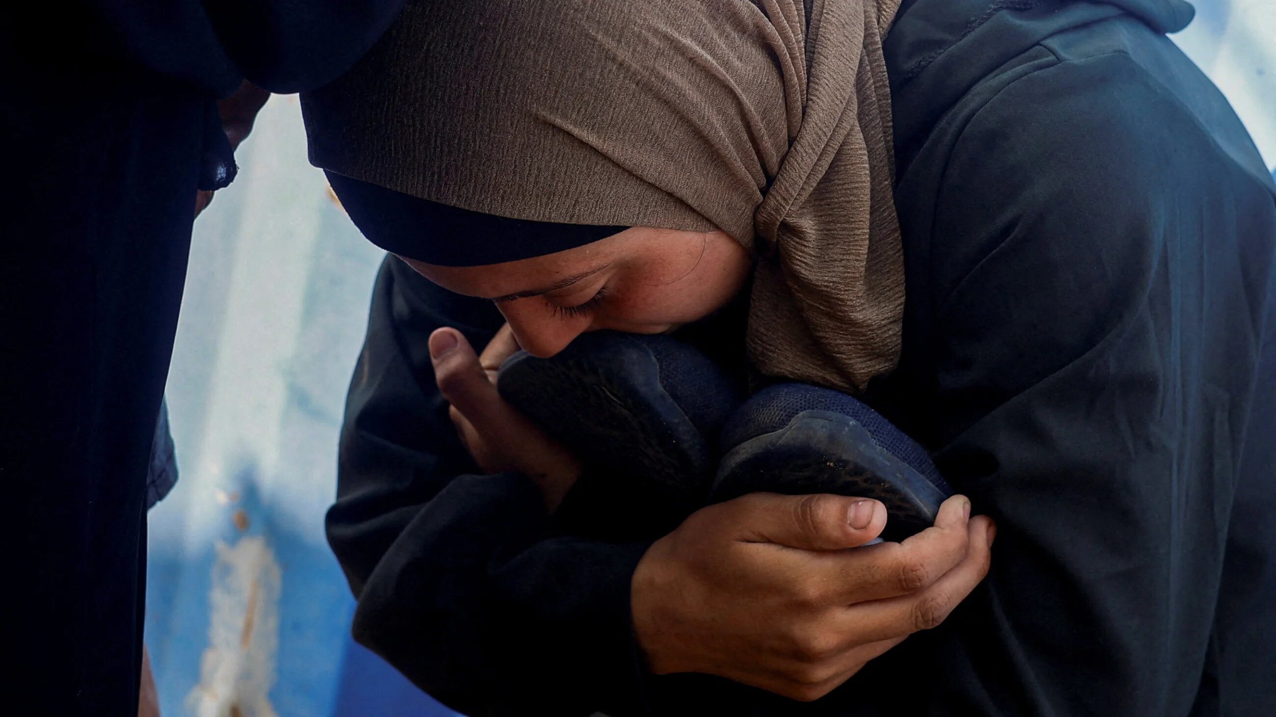 The widow of Palestinian man Nasser al-Frangi, who, according to medics, was killed in overnight Israeli strikes, kisses his shoes during his funeral at al-Awda Hospital in the central Gaza Strip, 28 September 2025 (Mahmoud Issa/Reuters)
