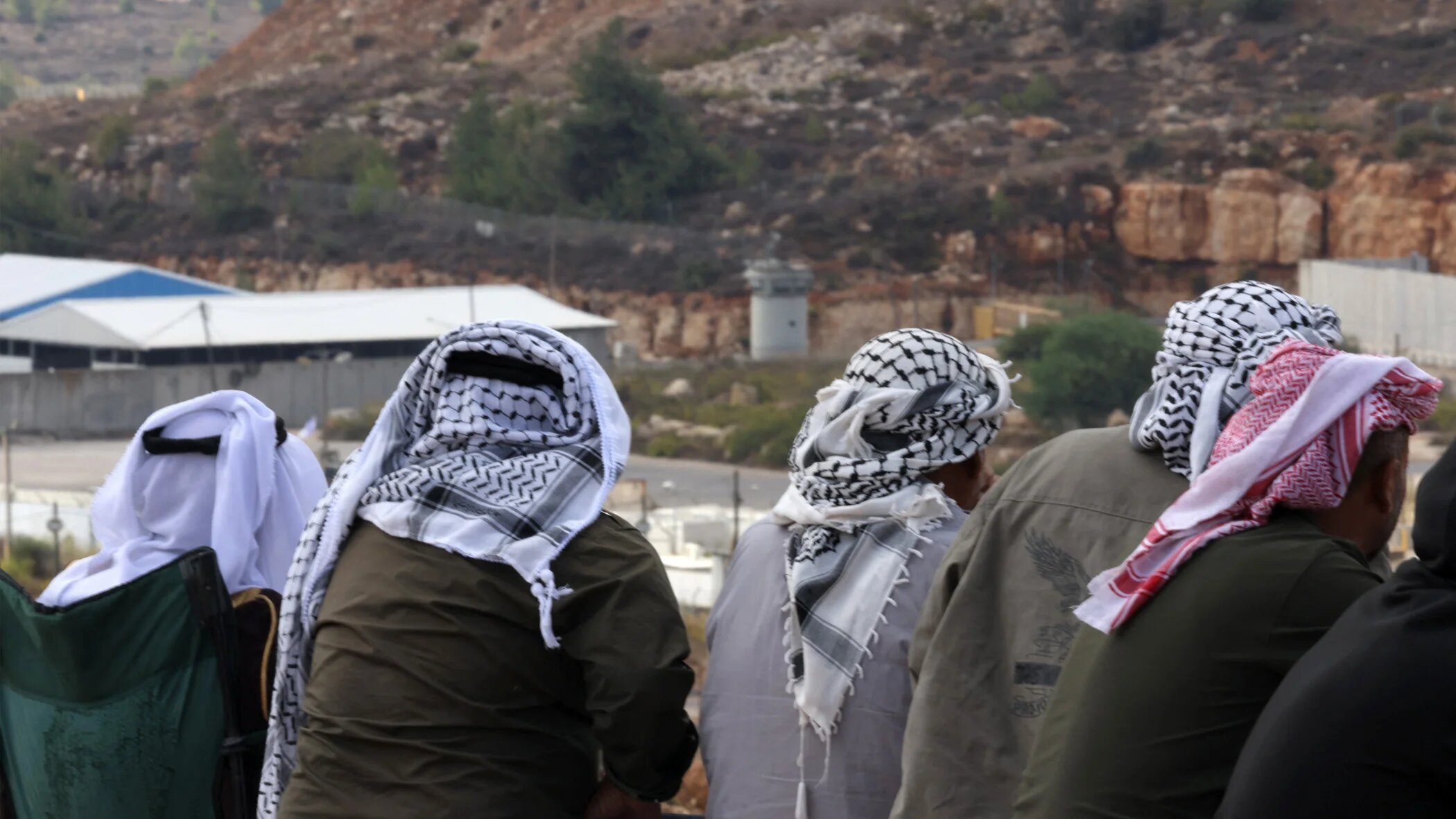 People gather to watch from a hilltop near Ofer military prison in the occupied West Bank on 13 October 2025, ahead of the release of Palestinian prisoners in exchange for captives held in Gaza (Hazem Bader/AFP)
