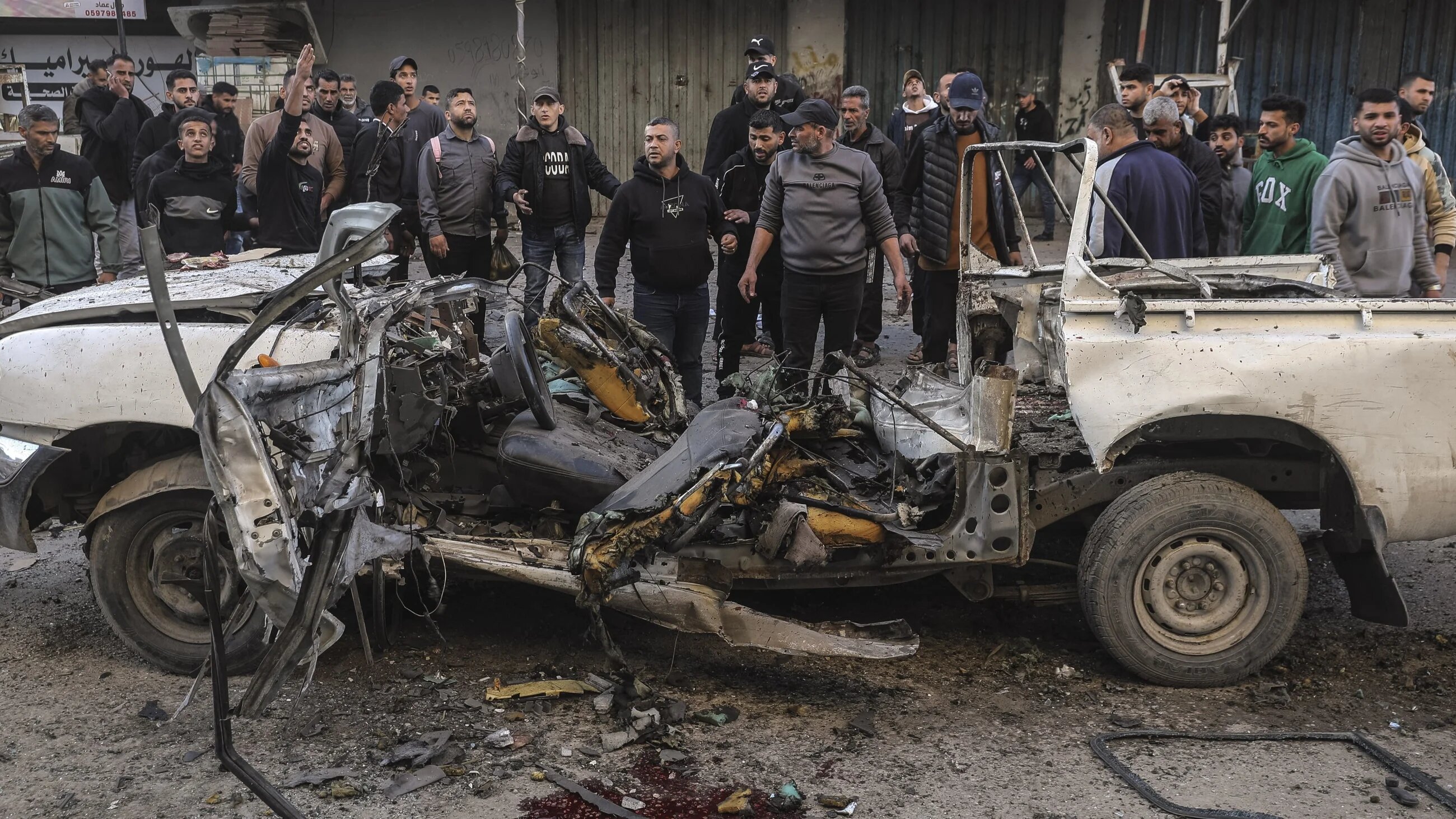 Palestinians gather around a destroyed police jeep that was targeted by an Israeli air strike in Nuseirat refugee camp, central Gaza Strip, on 22 March 2026 (AFP/Eyad Baba)