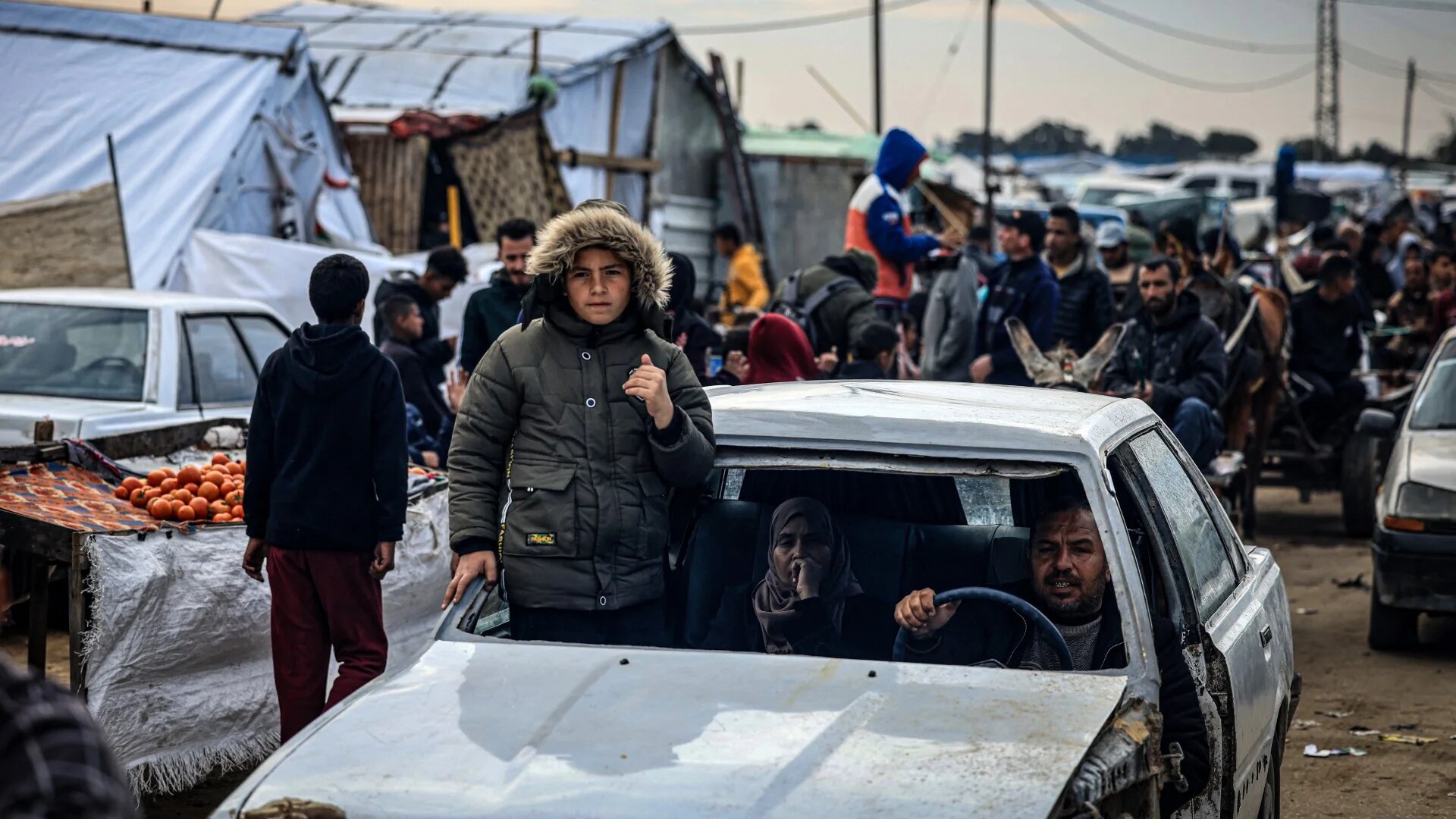 Palestinians use a damaged vehicle as they flee Khan Yunis in the southern Gaza Strip on 26 January 2024 (AFP)