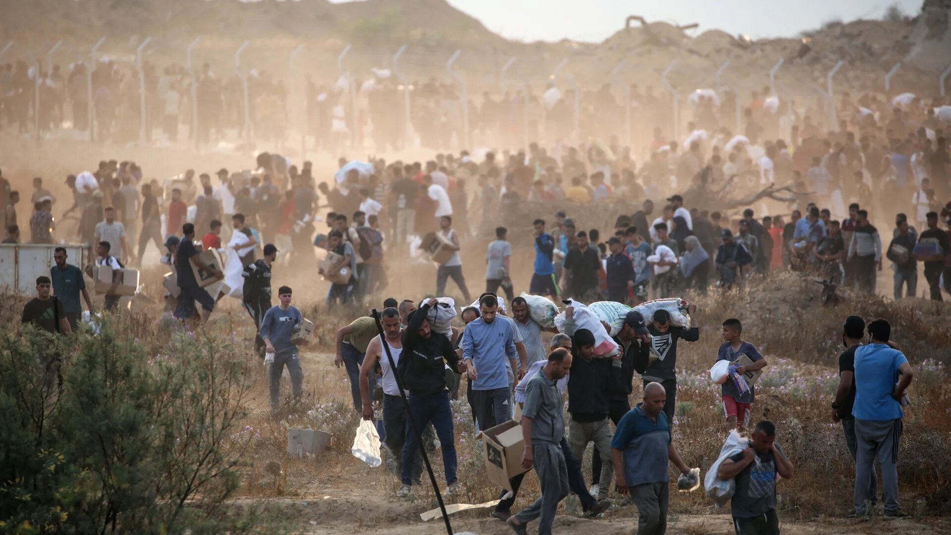 Palestinians carry relief supplies from the US-backed Gaza Humanitarian Foundation (GHF), in the central Gaza Strip on 8 June 2025 (AFP/Eyad Baba)