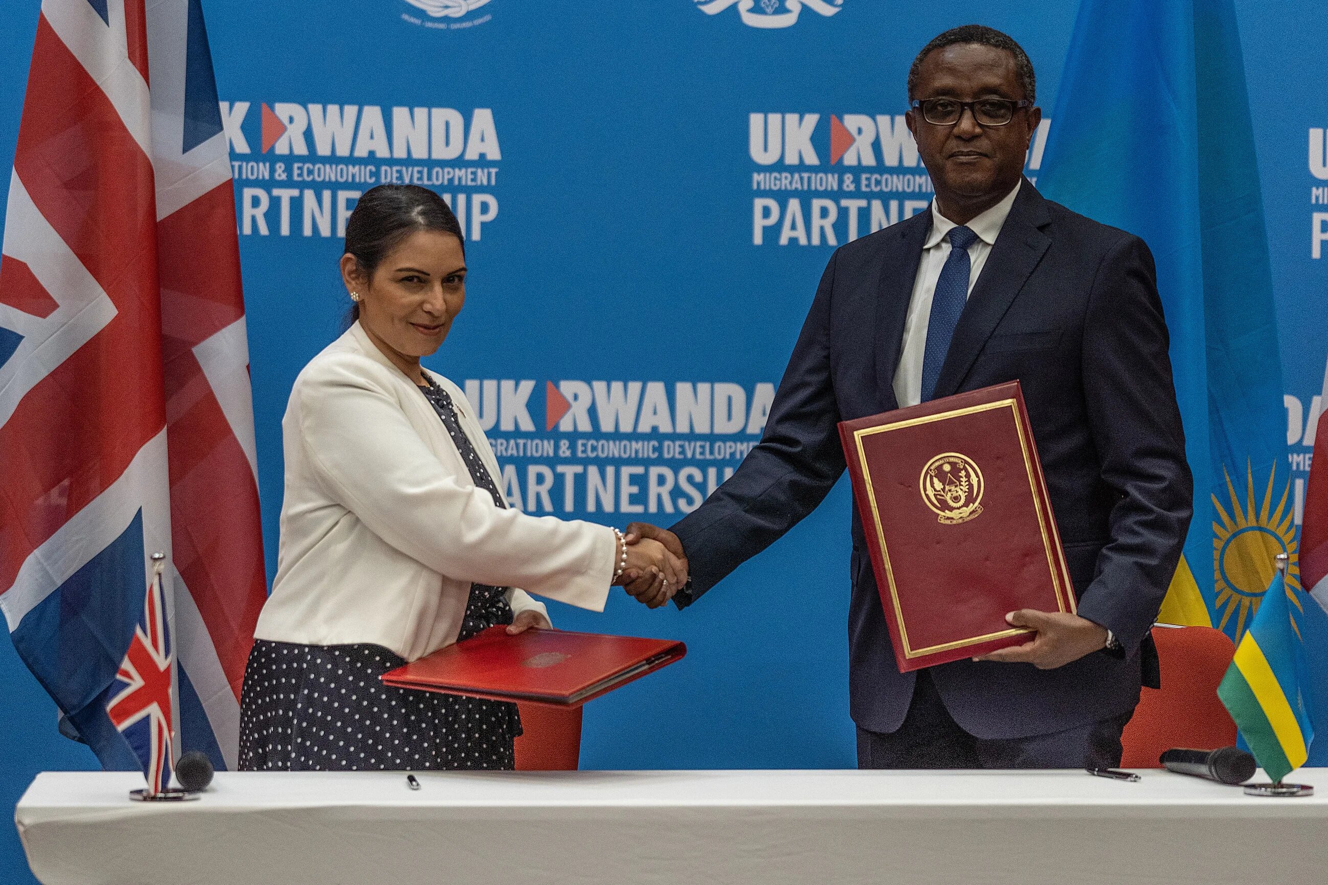 British Home Secretary Priti Patel and Rwandan Minister of Foreign Affairs and International Cooperation Vincent Biruta shake hands after signing an agreement in Kigali, Rwanda on 14 April 2022 (AFP)